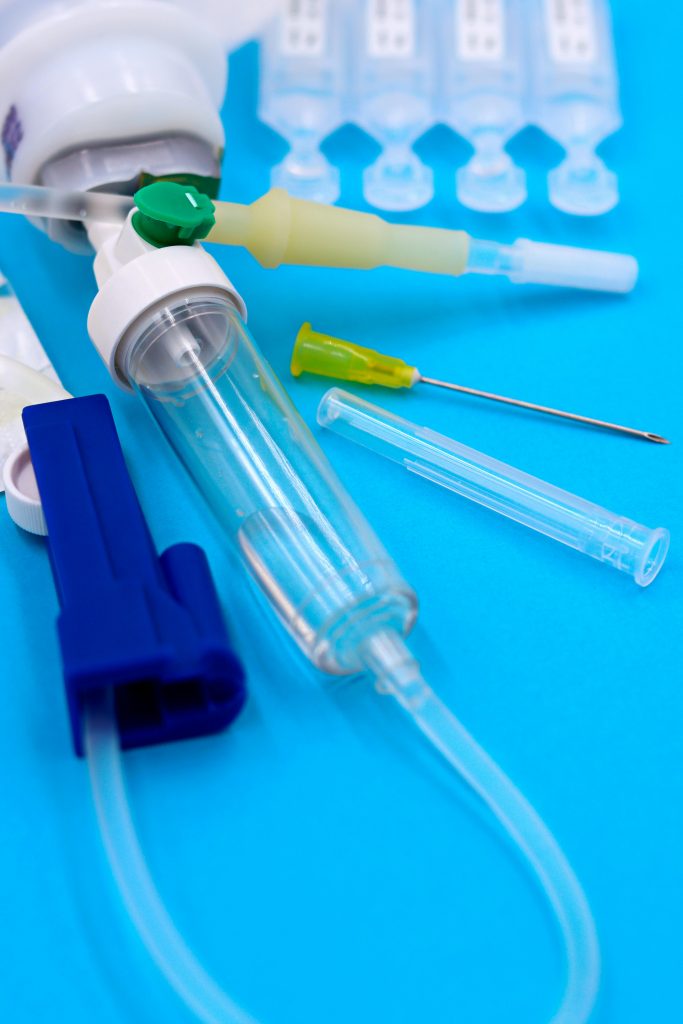 Close-up of medical syringes, needles, and tubes on a blue background.