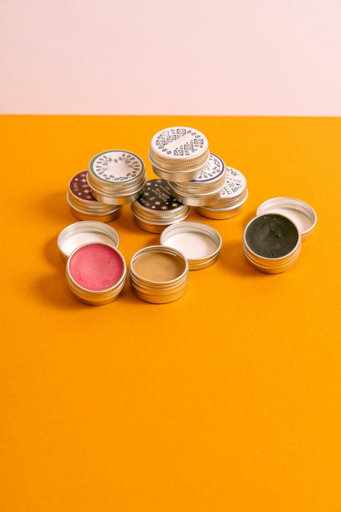 A vibrant assortment of lip balms and cosmetics in round containers on a two-tone background.