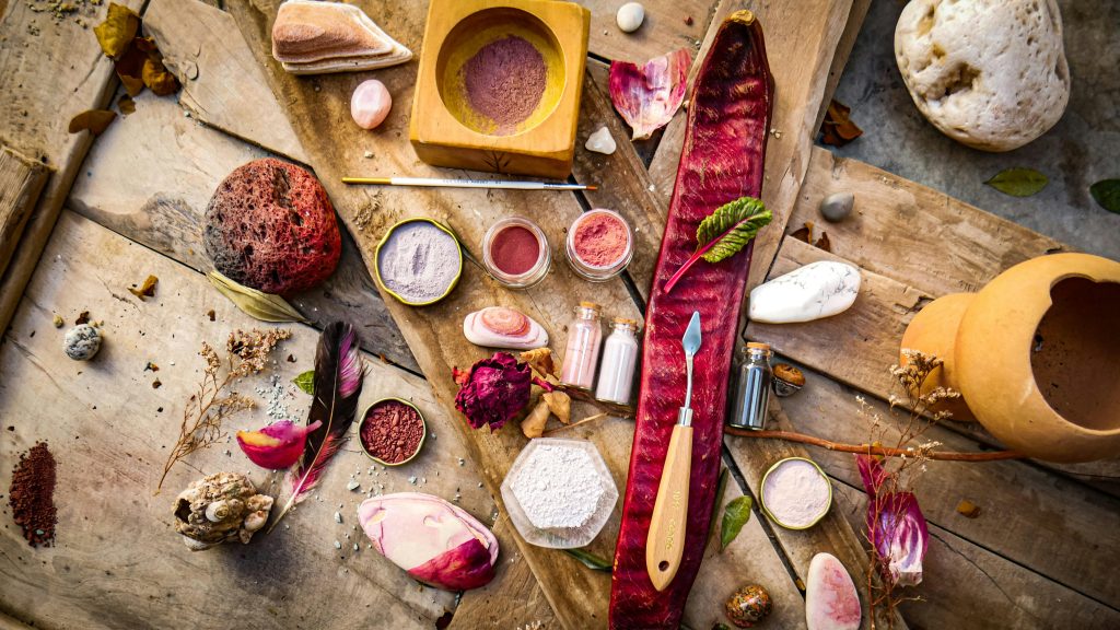 A creative flat lay with natural pigments, tools, and artistic elements on a wooden surface.