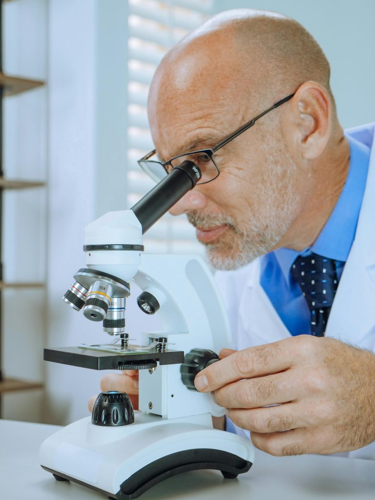 Adult male scientist using microscope for laboratory research.